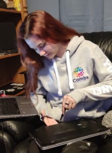 Photo shows Kiera, young woman, who is a member of Cambs Youth Panel, working on one of their laptops. 