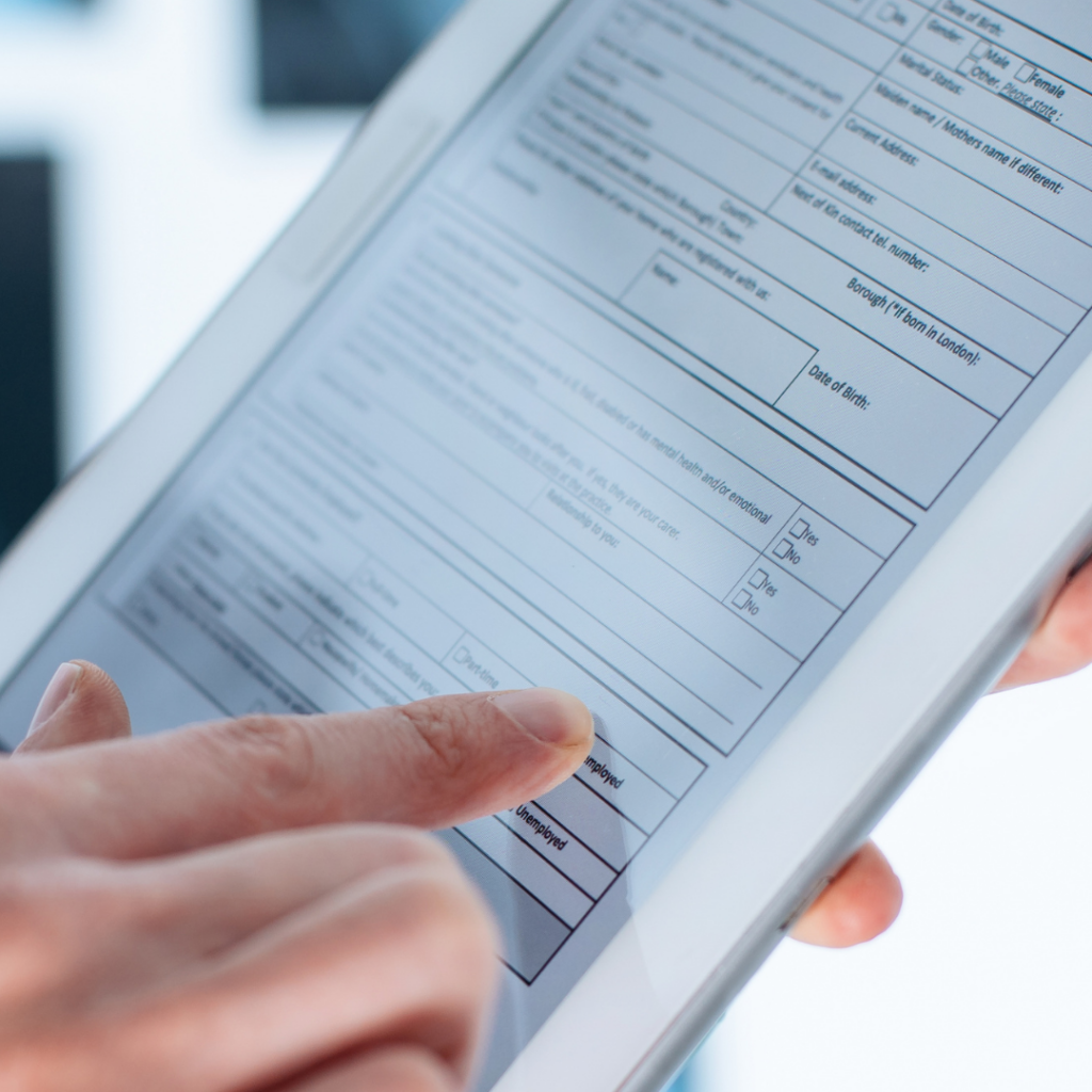 We see a close up of a digital tablet with a finger tapping the screen filling out an online form.