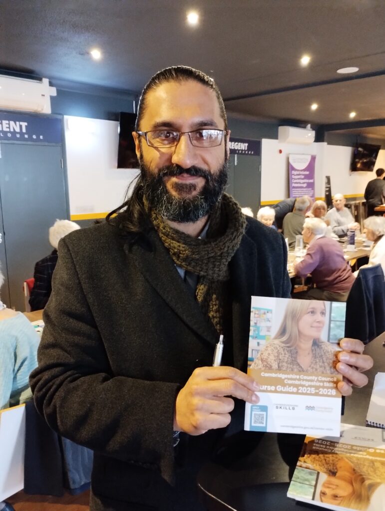 A man with dark hair and glasses holds a Cambridgeshire Skills leaflet